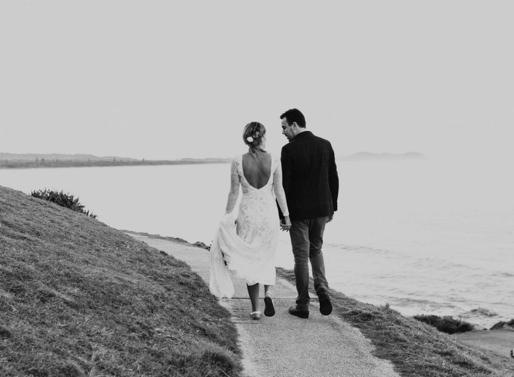 Newlyweds walk along a path on a Byron Bay headland